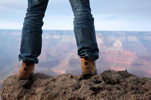 An image of a man standing on a mountain ledge 
